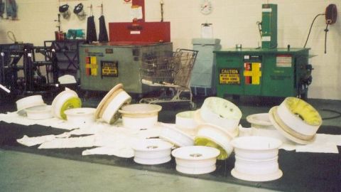 1988 Ford Bronco - A collection of car wheels are scattered on the floor in front of industrial machinery.