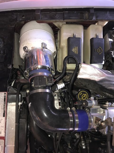 2000 Ford Explorer - The engine bay of a 2000 Ford Explorer shows a modified air intake system with a large chrome air filter housing and black silicone hoses c…