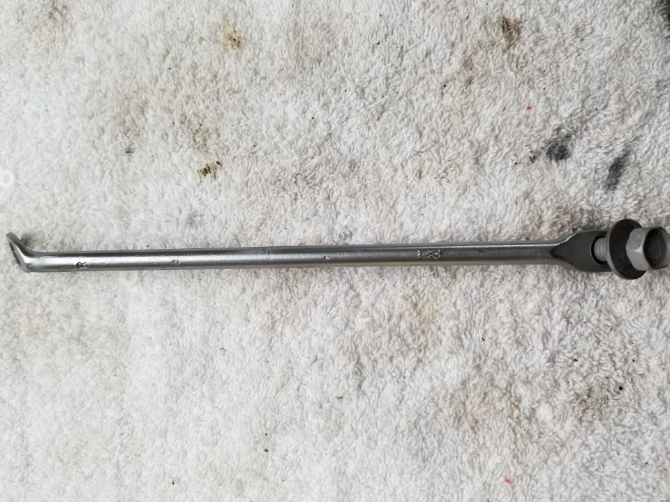 Metal spoke with hex nut and washer on one end, hooked end on the other, on a white towel.
