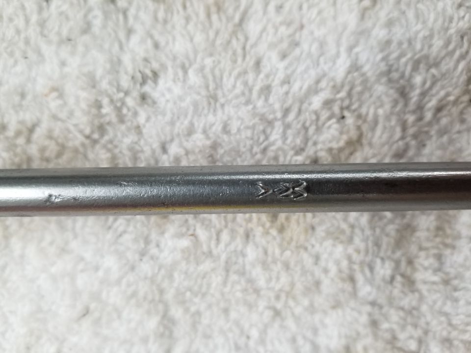 Close-up of a metal rod with "1-23" stamped on it.