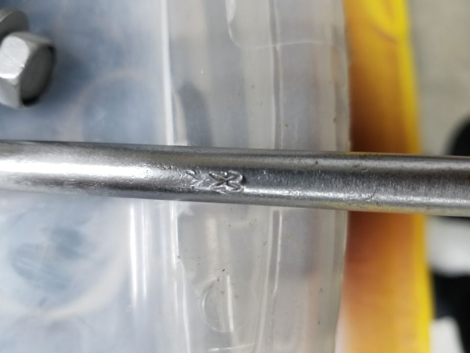 Close-up of a metal rod with a stamped logo.