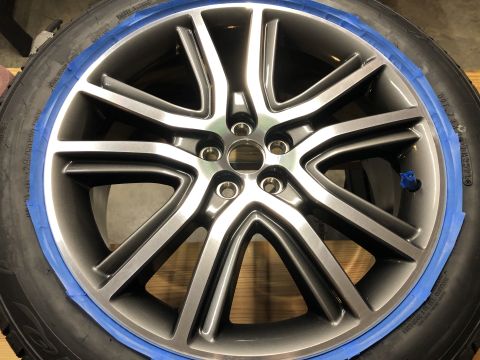 2019 Ford Everest - A close-up view of a gray alloy wheel with a blue tape masking around the rim, attached to a tire. The wheel has a multi-spoke design with…
