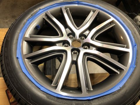2019 Ford Everest - A close-up view of a car wheel and tire assembly, with blue painter's tape applied around the rim of the wheel. The wheel has a multi-spoke…