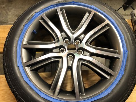 2019 Ford Everest - A close-up view of a gray alloy wheel with blue painter's tape around the rim, mounted on a tire. The wheel has a multi-spoke design and is…