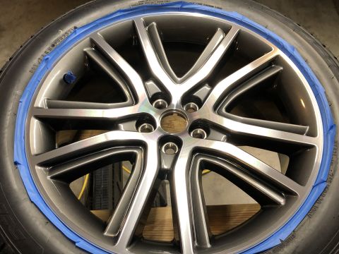 2019 Ford Everest - A close-up view of a gray alloy wheel with blue painter's tape applied around the tire's edge. The wheel has a multi-spoke design and is mo…