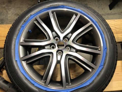 2019 Ford Everest - A close-up of a car wheel with blue painter's tape around the rim, ready for detailing or painting. The wheel has a multi-spoke design and…