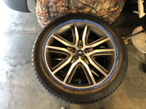 2019 Ford Everest - A close-up view of a silver and black alloy wheel with a Ford logo in the center, covered with blue painter's tape around the rim. The whee…