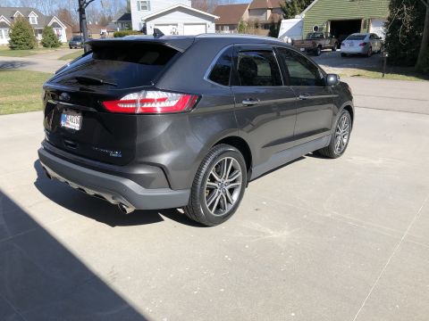 2019 Ford Everest - The rear passenger side of a dark gray Ford Edge is parked on a concrete driveway in front of a residential house. The vehicle has tinted w…