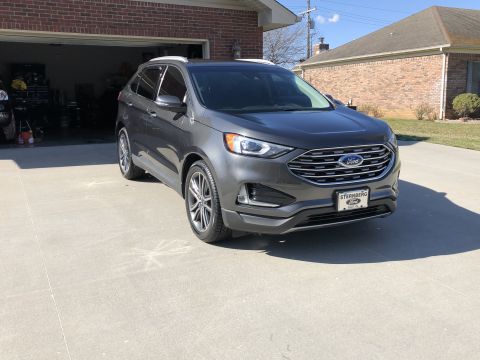 2019 Ford Everest - A gray Ford Edge SUV is parked in front of a brick garage on a sunny day.