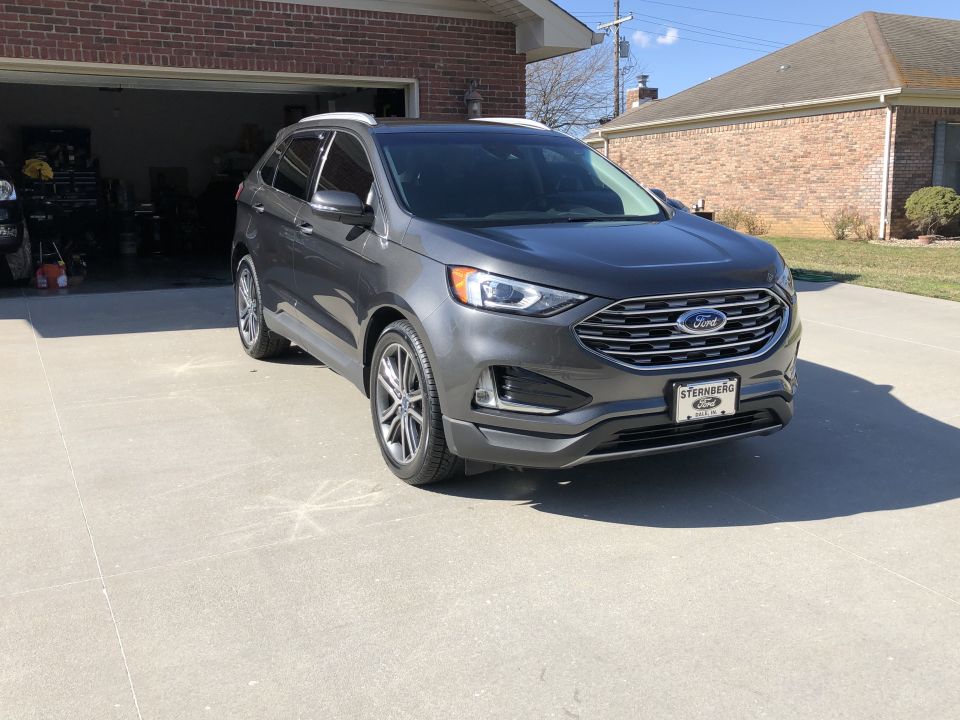 Gray Ford Edge parked in driveway, front 3/4 view. Visible license plate frame reads 'STERNBERG'