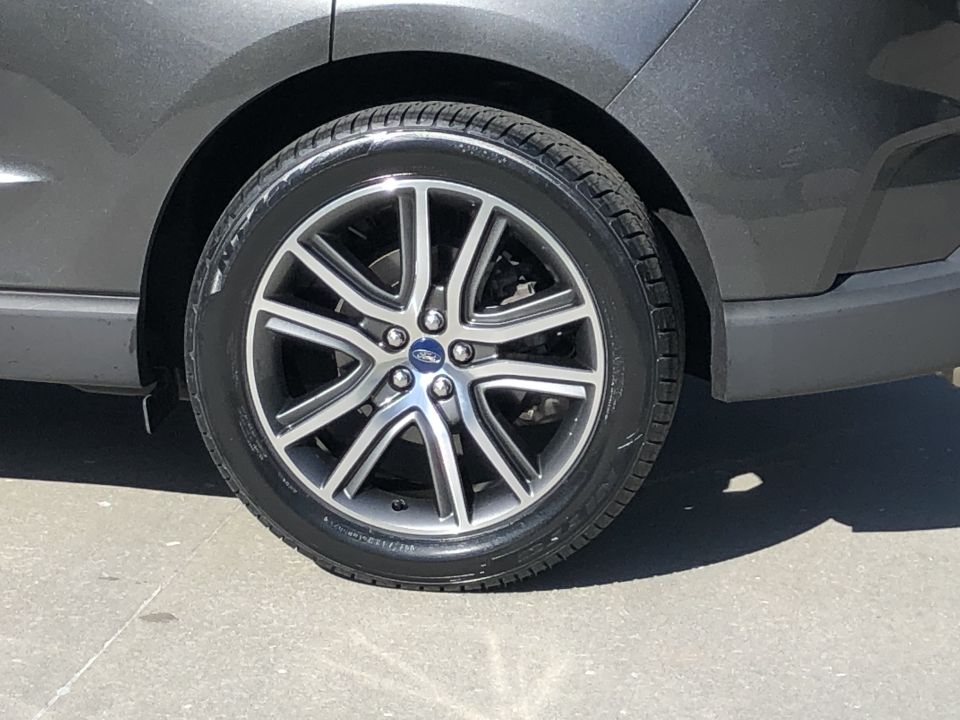 Close-up of a gray Ford SUV's wheel and tire. The wheel has a silver and black finish