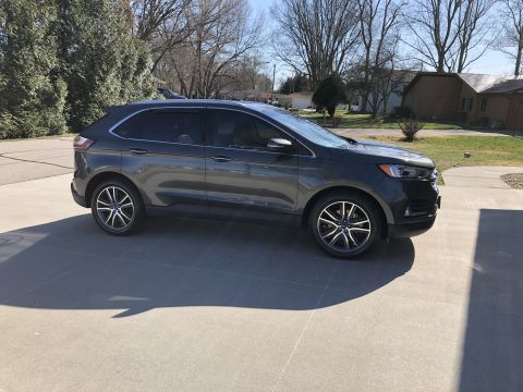 2019 Ford Everest - A dark gray Ford Edge SUV is parked on a concrete driveway in front of a residential house.