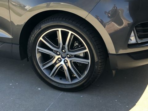 2019 Ford Everest - The front wheel and lower body panel of a dark gray SUV are shown in this close-up shot.