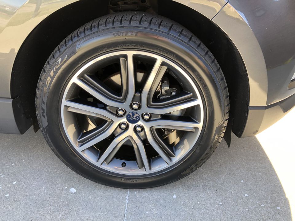 Gray Ford wheel with five split spokes and a Ford logo, mounted on a dark gray vehicle