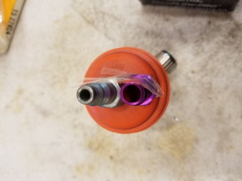 1973 Chevrolet Camaro - This image shows an orange fuel pressure regulator with purple and silver fittings, likely a vehicle part.