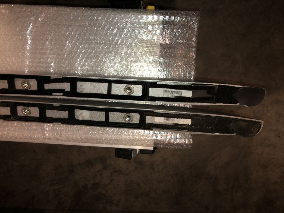 Pair of silver roof rack rails with black trim and mounting points