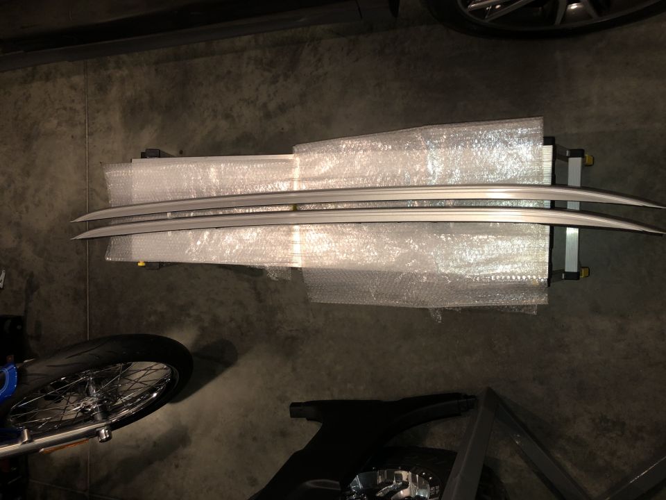 Pair of silver roof rails packaged in bubble wrap on a stand