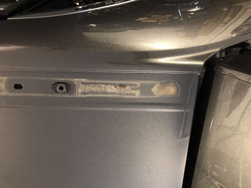 Close-up of a car's gray door panel showing a mounting point and a recessed area with some debris