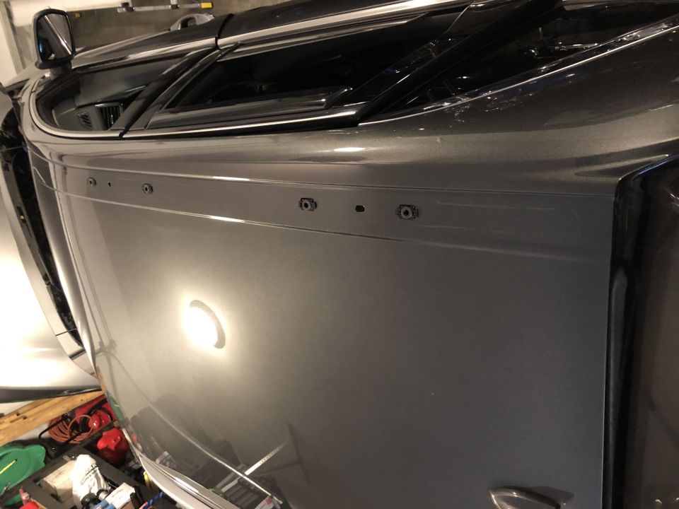 Gray SUV side panel with multiple mounting holes and a reflection of a light