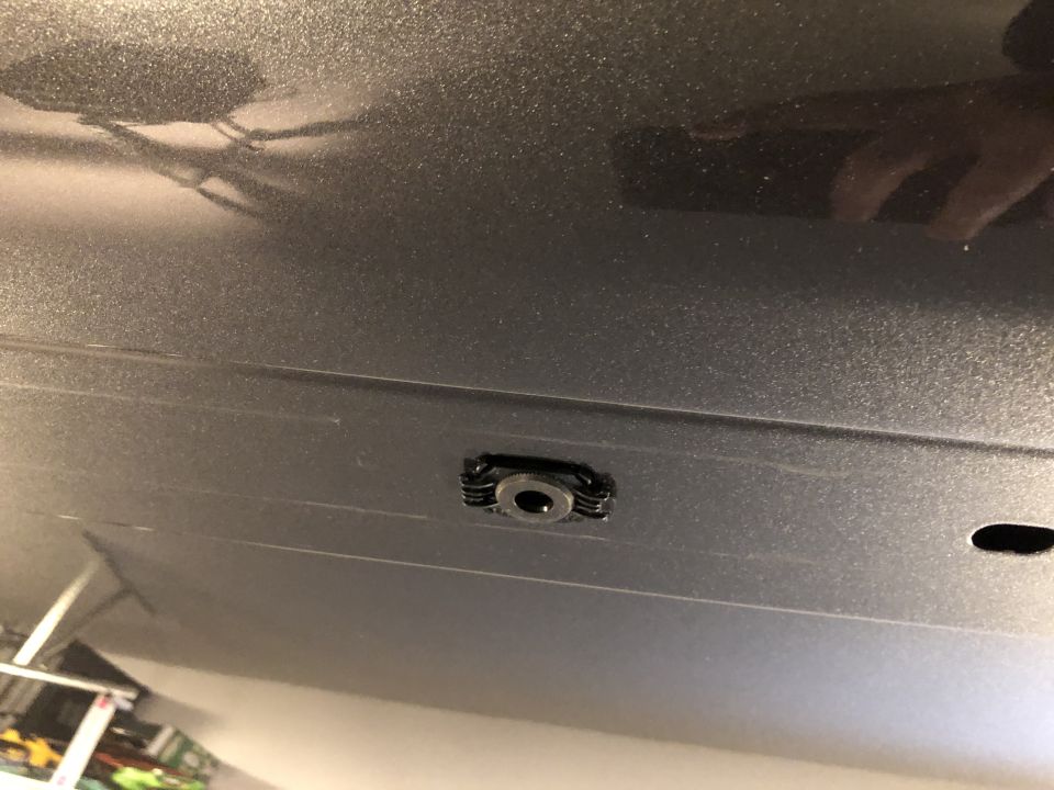 Close-up of a mounting point on the underside of a dark-colored vehicle