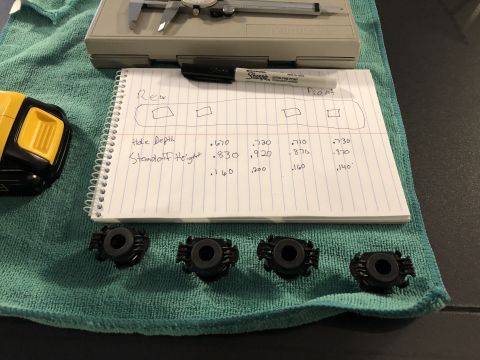 2019 Ford Everest - Four black plastic mounting brackets are laid out with a notebook detailing measurements for installation.