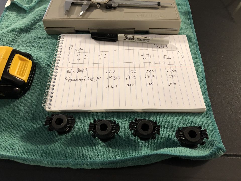 Four black plastic mounting brackets and a notebook with measurements for hole depth and standoff height