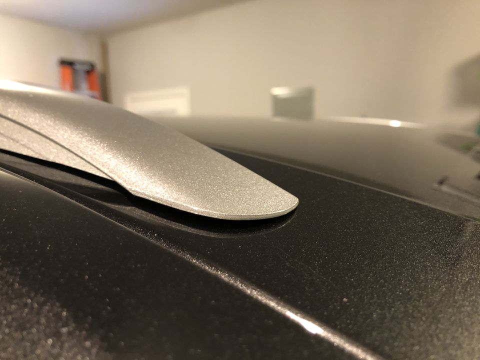 Close-up of a silver roof rack component on a dark vehicle