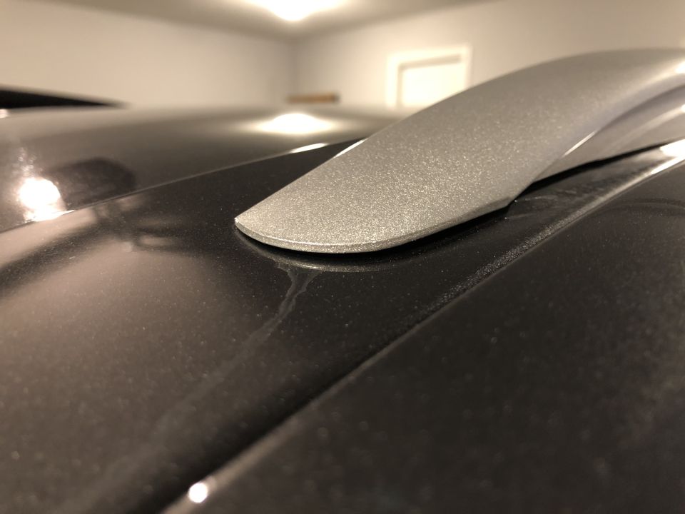 Close-up of a silver roof rack rail on a dark car's roof