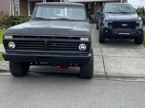1978 Ford Bronco - A black 1978 Ford Bronco is parked in a driveway, its front grille and headlights clearly visible.