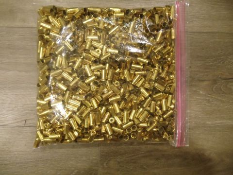 1994 Ford Bronco - A large quantity of brass shell casings fills a plastic bag, resting on a wooden floor.