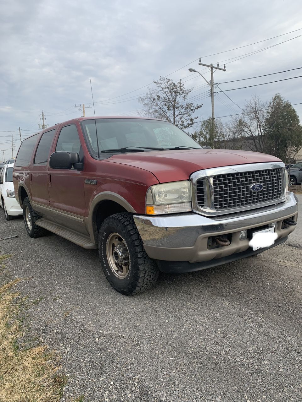 Red 2002 Ford Excursion parked on gravel lot