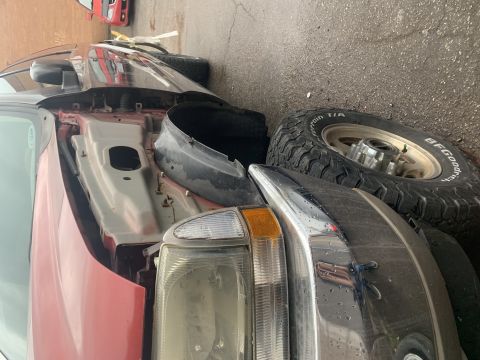 2002 Ford Excursion - The front of a 2002 Ford Super Duty truck is shown, with parts removed and a spare tire nearby.
