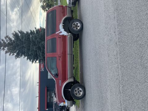 2002 Ford Excursion - Side view of a red and tan Ford Excursion SUV parked on a street.
