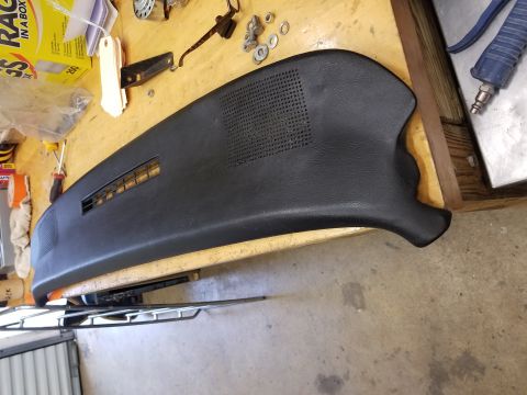 1973 Chevrolet Camaro - A black dashboard section with air vents and a speaker grille is shown, resting on a wooden surface with various tools and parts.
