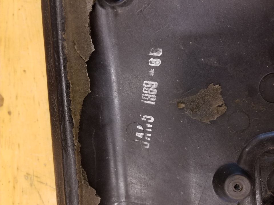 Black plastic part with a stamped date: JAN 5 1989 - 6D. Some material is peeling off the edge