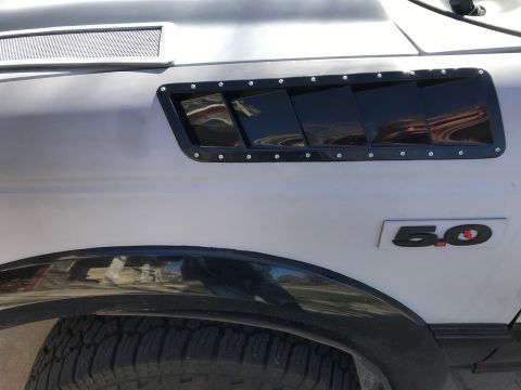 2000 Ford Explorer - A close-up shot of a vehicle's side panel, aftermarket window louvers and a prominent '5.0' emblem.