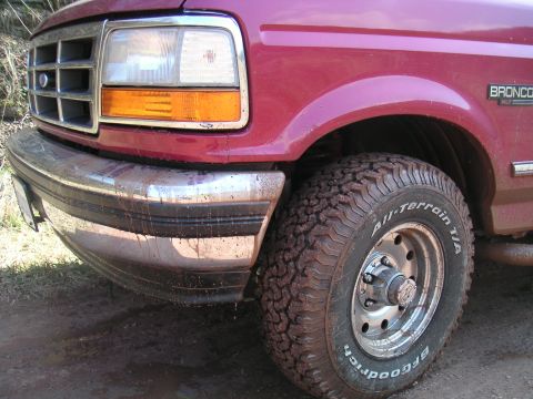 1994 Ford Bronco - The front driver's side of a red Bronco is shown, covered in mud from off-roading.