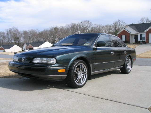 Dark green Infiniti Q45 sedan with chrome wheels parked on a concrete driveway