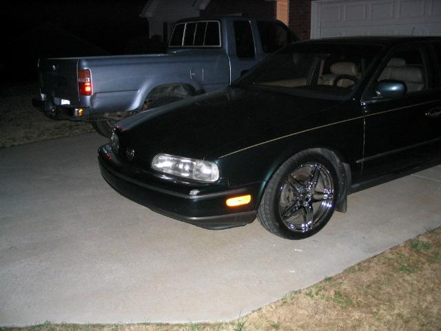 Dark sedan with chrome wheels parked next to a blue pickup truck