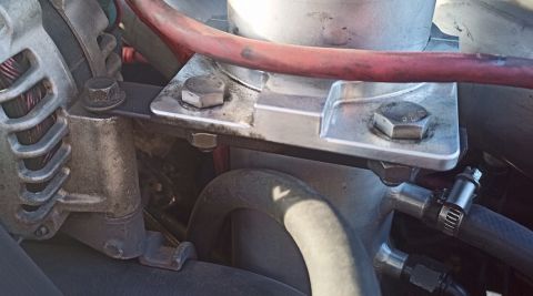 2001 Ford Excursion - Close-up view of an engine component with a metal bracket and red hose attached.