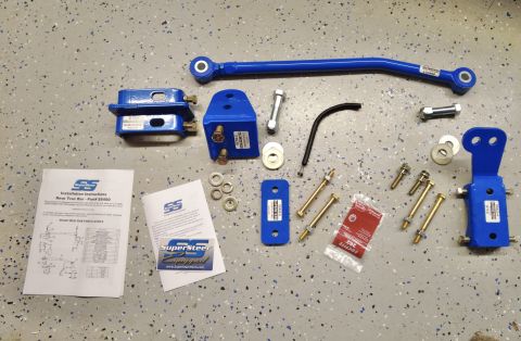 2015 Ford F-550 - A Supersteer rear trac bar kit, including various blue metal components and hardware, is displayed on a concrete floor.