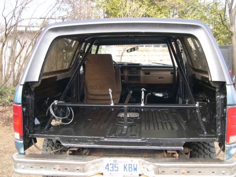 1986 Ford Bronco - The interior of this 1986 Ford Bronco features a custom roll cage and a stripped-down cargo area.