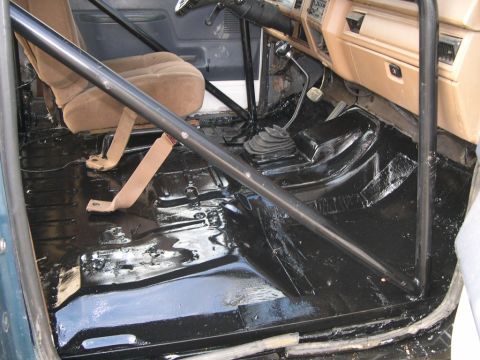1986 Ford Bronco - Interior of a 1986 Ford Bronco with a roll cage and freshly painted floor.