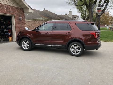 2016 Ford Explorer - A maroon Ford Explorer is parked in front of a brick garage with a basketball hoop in the background.