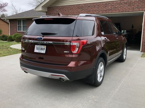 2016 Ford Explorer - The rear of a maroon 2016 Ford Explorer is visible, parked in a driveway with a garage in the background.