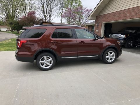 2016 Ford Explorer - Side view of a red 2016 Ford Explorer parked outside a brick house with a garage.