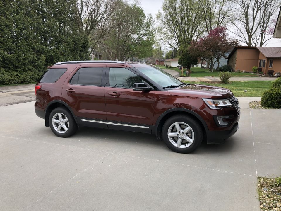 Brown 2016 Ford Explorer parked on a concrete driveway, side view