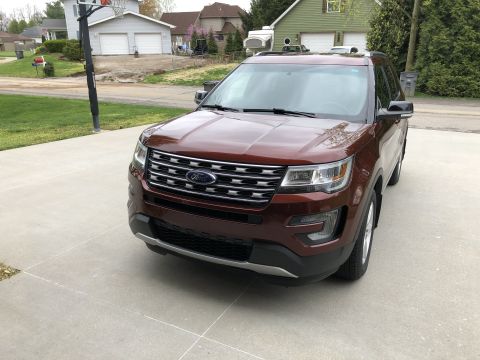 2016 Ford Explorer - A brown 2016 Ford Explorer is parked on a concrete driveway in front of a residential garage.