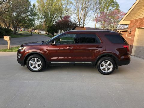 2016 Ford Explorer - Side profile of a red 2016 Ford Explorer parked in a suburban driveway.