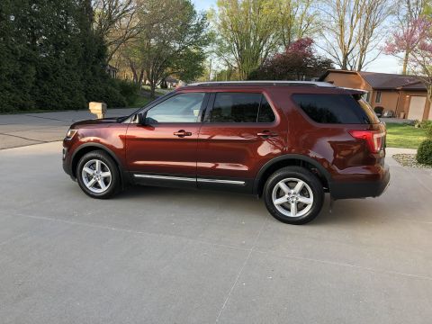 2016 Ford Explorer - A brown 2016 Ford Explorer is parked on a paved surface in front of a residential house.